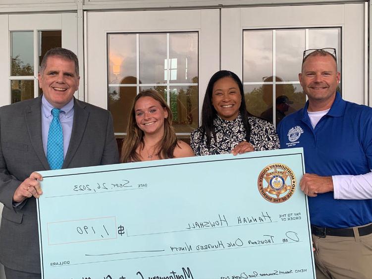 Montgomery County Sheriff's Office Chief Deputy Adam Berry, county Commissioner Jamila Winder, 学生汉娜·豪沙尔, and Sheriff Sean Kilkenny with Hannah's scholarship check